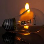 Lâmpada e vela acesa simbolizando falta de energia elétrica.