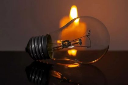 Lâmpada e vela acesa simbolizando falta de energia elétrica.