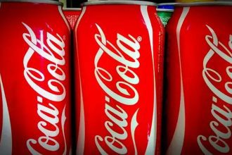 Latas de Coca-Cola vermelhas e brancas em exibição, prontas para consumo.