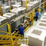 Linha de produção industrial da Electrolux em Manaus, com funcionários trabalhando.