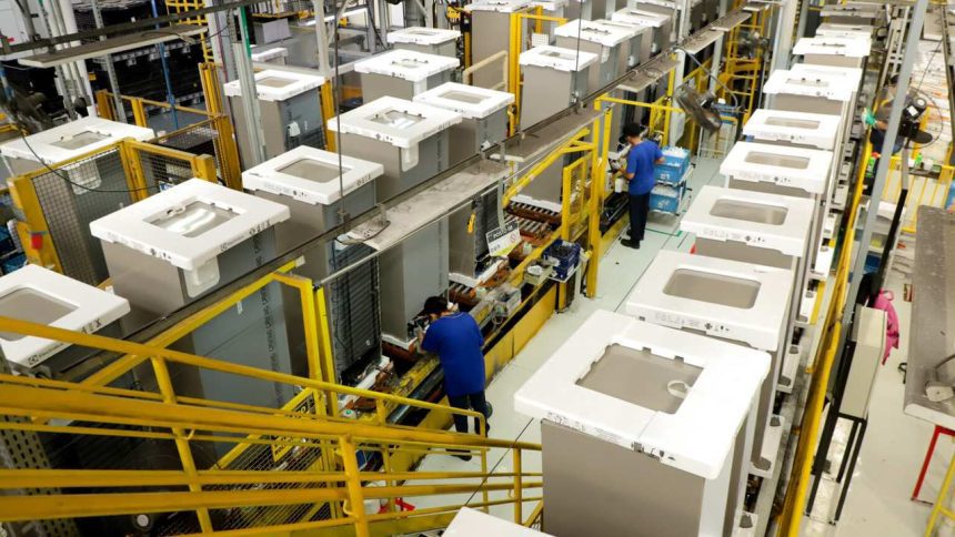 Linha de produção industrial da Electrolux em Manaus, com funcionários trabalhando.