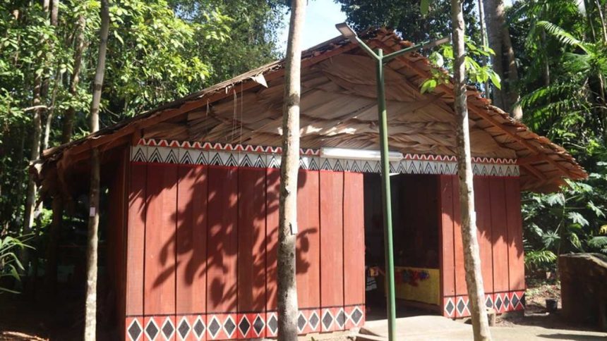Maloca indígena no Bosque da Ciência, com arquitetura tradicional e elementos decorativos.