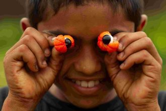 Menino com guaraná nos olhos, sorrindo para a câmera, representando a Rota do Guaraná.