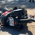 Motocicleta acidentada no chão, com danos visíveis.