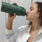Mulher bebendo água de garrafa verde