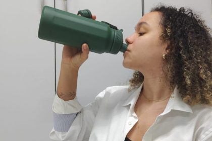 Mulher bebendo água de garrafa verde