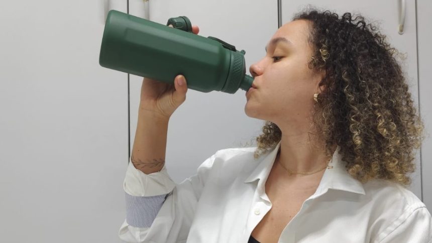 Mulher bebendo água de garrafa verde