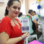 Mulher segura panfleto do Crédito Solidårio em evento no Bairro da Paz.