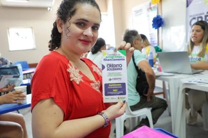 Mulher segura panfleto do Crédito Solidário em evento no Bairro da Paz.