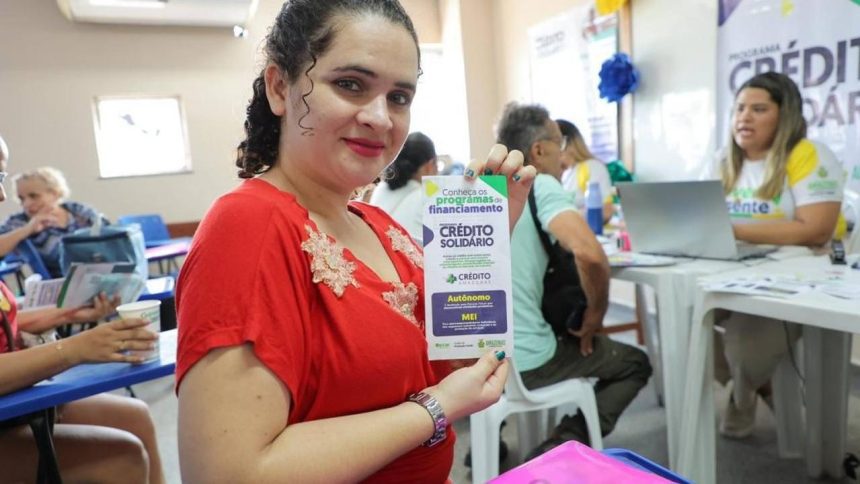 Mulher segura panfleto do Crédito Solidário em evento no Bairro da Paz.