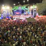 Multidão em evento cultural noturno em Manaus, Amazonas, com palco e arquibancadas.