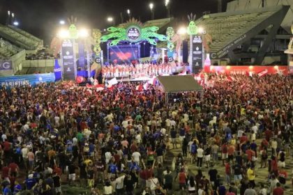 Multidão em evento cultural noturno em Manaus, Amazonas, com palco e arquibancadas.