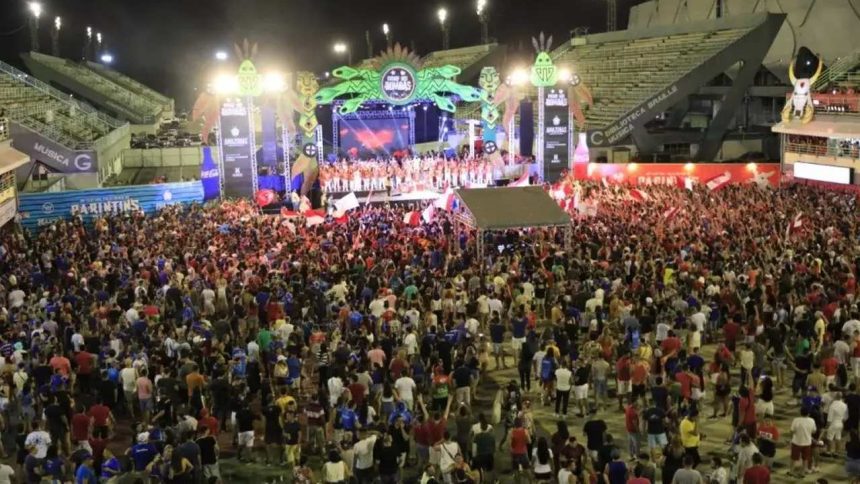 Multidão em evento cultural noturno em Manaus, Amazonas, com palco e arquibancadas.
