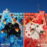 Mural colorido em edifício com bois e figuras festivas, representando o Festival de Parintins.