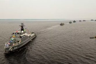 Navios da Marinha do Brasil navegando em formação no rio em Manaus.