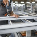 Operário perfurando estrutura de metal em fábrica de Manaus