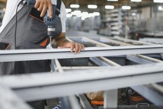 Operário perfurando estrutura de metal em fábrica de Manaus