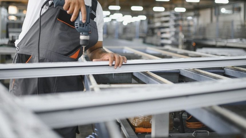 Operário perfurando estrutura de metal em fábrica de Manaus