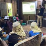 Palestra sobre projeto de sustentabilidade em Manicoré, com apresentação em tela e participantes.