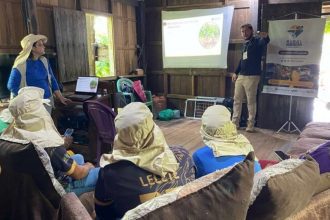 Palestra sobre projeto de sustentabilidade em Manicoré, com apresentação em tela e participantes.