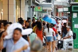 Pessoas caminham em rua movimentada, possivelmente após recebimento de salário.