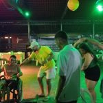 Pessoas dançando forró em casa de show em Manaus, com luzes verdes e balão amarelo.
