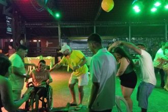 Pessoas dançando forró em casa de show em Manaus, com luzes verdes e balão amarelo.