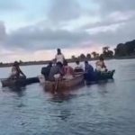 Pessoas em barcos em rio em Autazes após tragédia.