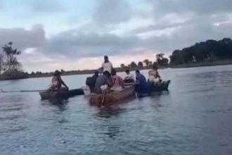 Pessoas em barcos em rio em Autazes após tragédia.