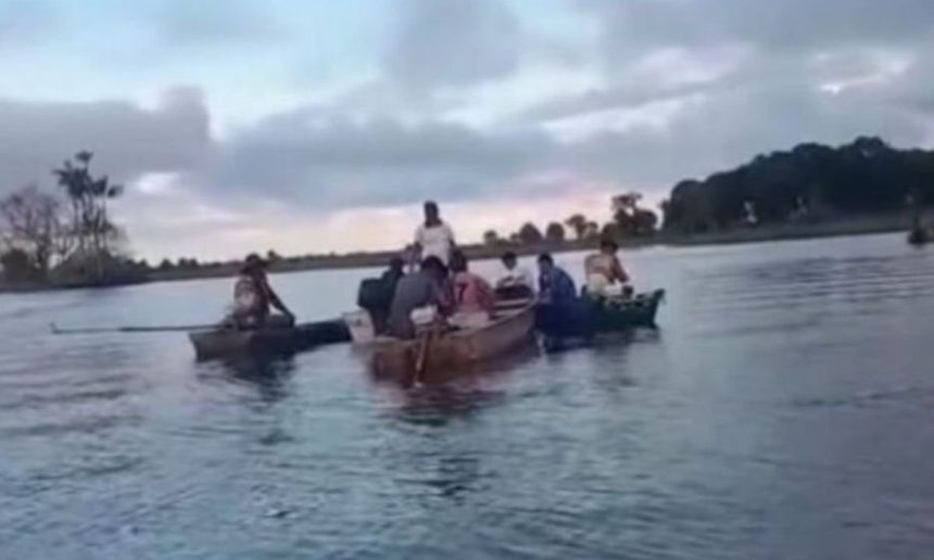 Pessoas em barcos em rio em Autazes após tragédia.
