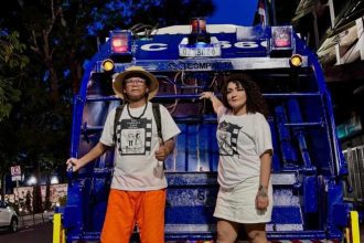 Pessoas em frente a um veículo azul, possivelmente durante evento.