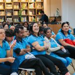 Pessoas reunidas em sala de aula, sorrindo e atentas.