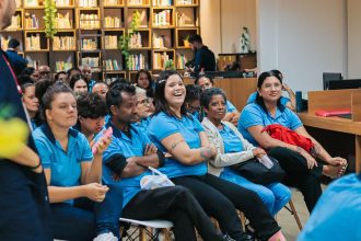 Pessoas reunidas em sala de aula, sorrindo e atentas.