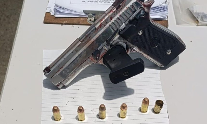 Pistola apreendida em cena de crime, com munição e vestígios de sangue.
