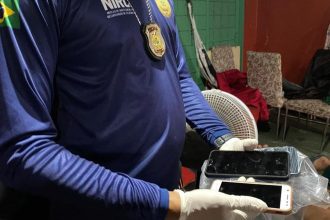 Policial segura celulares apreendidos durante operação policial.