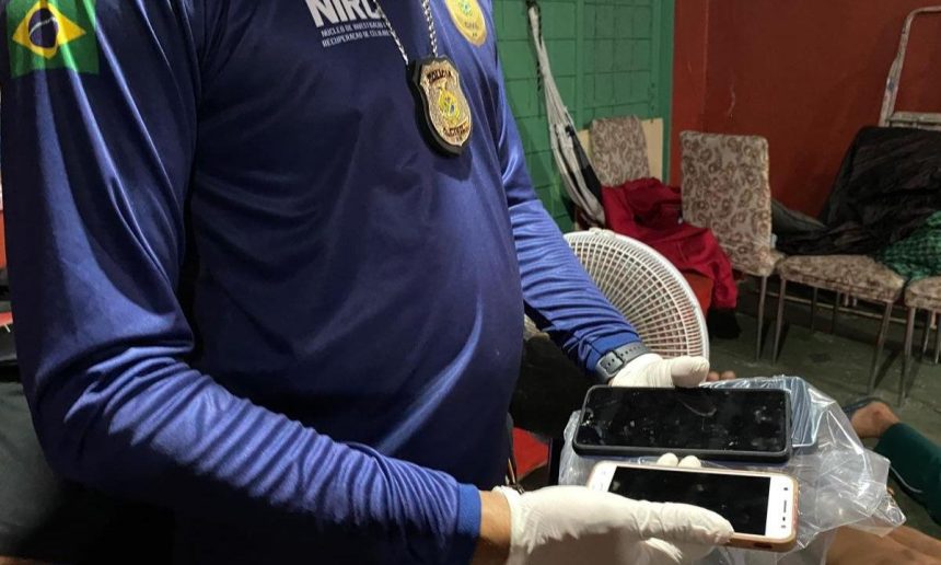 Policial segura celulares apreendidos durante operação policial.
