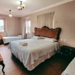 Quarto de hotel com cama grande, camas de solteiro e decoração clássica.