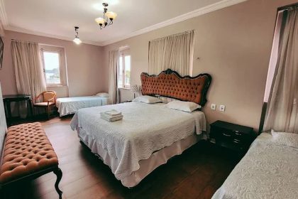 Quarto de hotel com cama grande, camas de solteiro e decoração clássica.