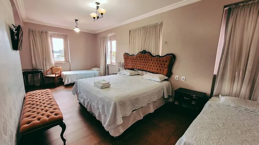 Quarto de hotel com cama grande, camas de solteiro e decoração clássica.