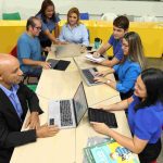 Reunião de equipe com pessoas trabalhando em laptops e tablets.