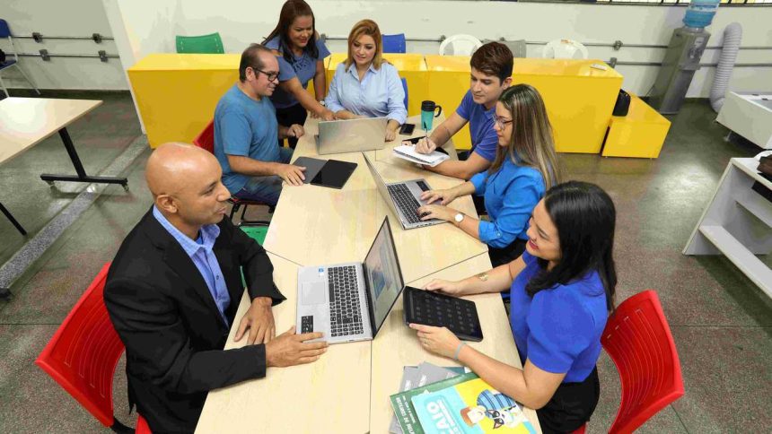 Reunião de equipe com pessoas trabalhando em laptops e tablets.