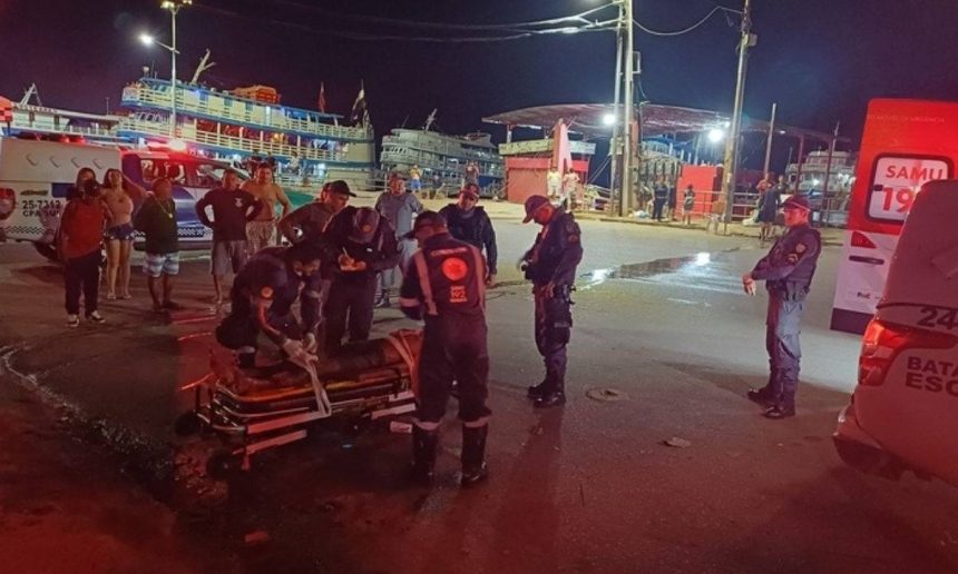 Socorristas atendem vítima de agressão em área portuária em Manaus, com ambulância e pessoas ao redor.