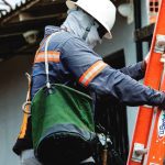 Supervisor técnico de manutenção elétrica com equipamentos de segurança e escada.