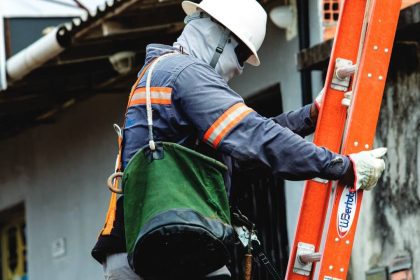 Supervisor técnico de manutenção elétrica com equipamentos de segurança e escada.