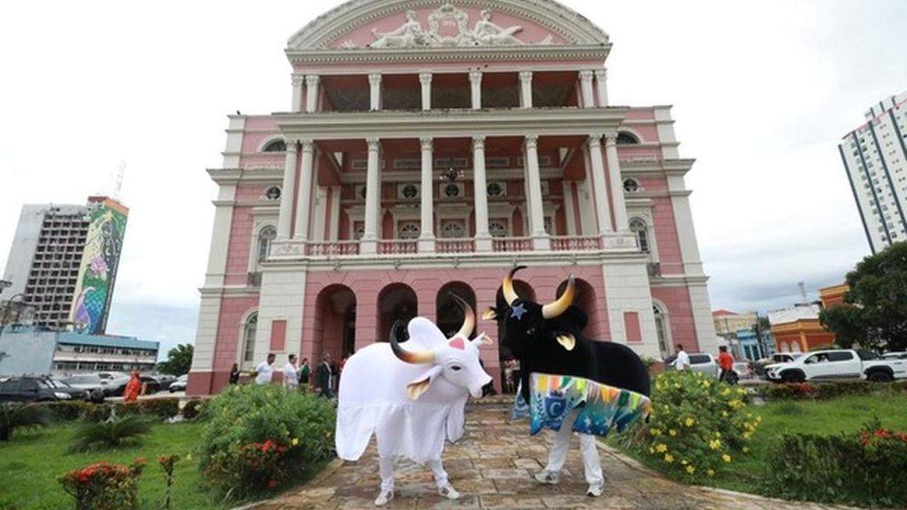 Teatro Amazonas com dois bois-bumbás em frente.
