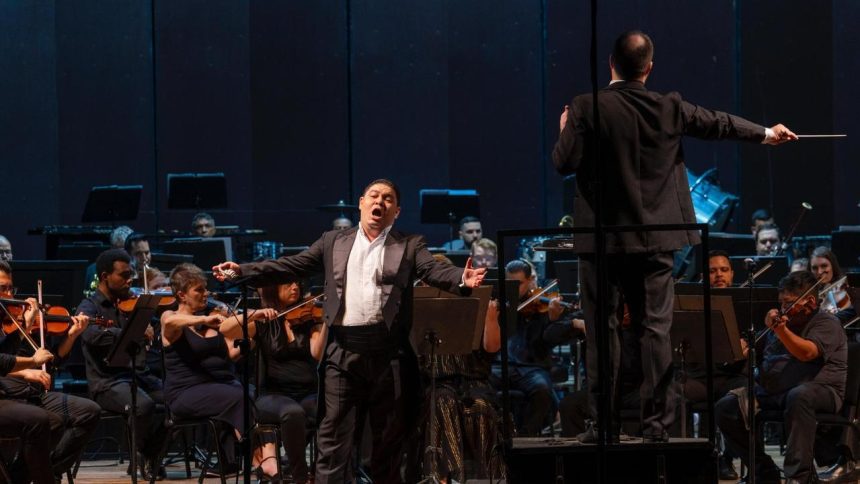 Tenor se apresenta em concerto de música clássica, com orquestra e maestro.