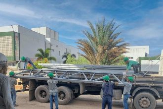 Trabalhadores descarregando materiais de construção de um caminhão em Manaus, construtora.
