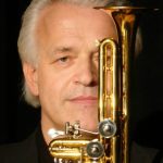 Trompetista alemão com trompete dourado, em close.