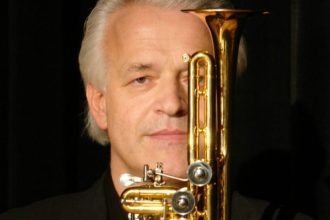 Trompetista alemão com trompete dourado, em close.