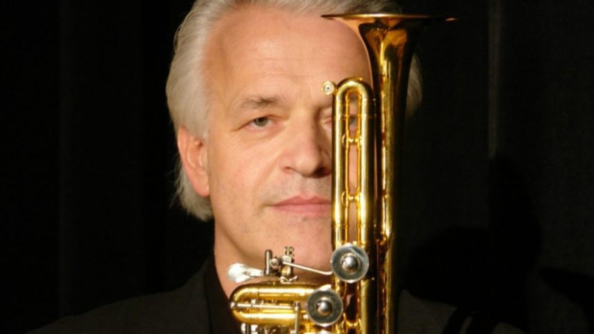 Trompetista alemão com trompete dourado, em close.